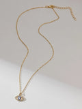 Full gold-tone evil eye necklace with extender chain laid on a light background