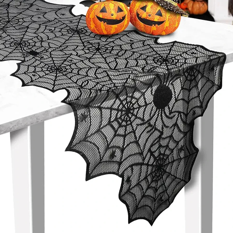 Black spiderweb lace runner draped over a white table with pumpkin decorations